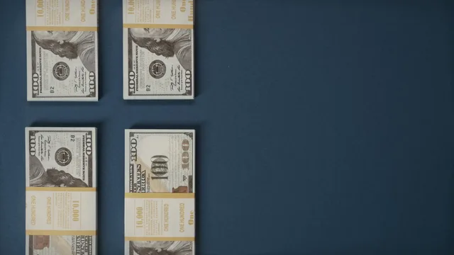 Bundles of US dollar bills neatly stacked on a blue surface, showcasing wealth and finance. Retainer or project fee, which digital PR pricing model suits your agency