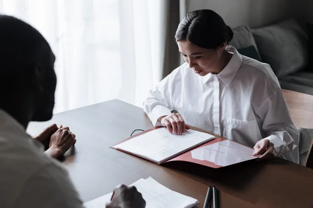 Professional businesswoman discussing documents with colleague at a desk indoors. How to build a digital PR skills forecast